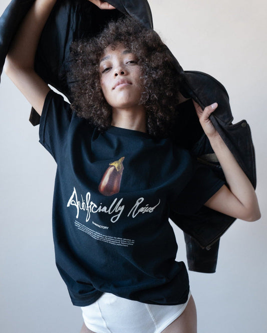 Unisex black 'Artificially Raised' t-shirt by 10:AM Factory, featuring a bold big eggplant graphic print and 10:AM logo, crafted from high-quality, soft cotton for a clean, modern look.