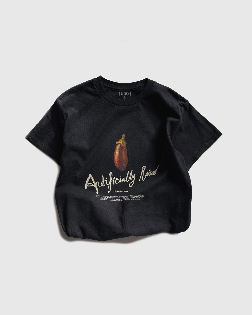 Unisex black 'Artificially Raised' t-shirt by 10:AM Factory, featuring a bold big eggplant graphic print and 10:AM logo, crafted from high-quality, soft cotton for a clean, modern look.