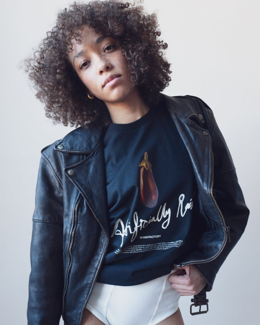 Unisex black 'Artificially Raised' t-shirt by 10:AM Factory, featuring a bold big eggplant graphic print and 10:AM logo, crafted from high-quality, soft cotton for a clean, modern look.